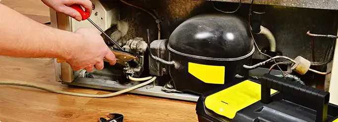 Refrigerator repair technician fixing the compressor and wiring in West Jordan, UT