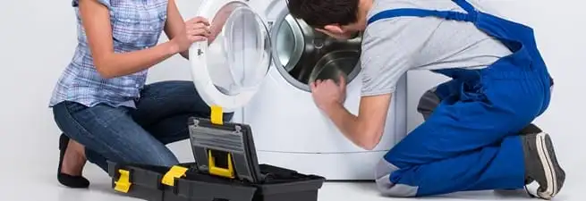 Washer repair technician inspecting a front-load washing machine with tools in Salt Lake City, UT