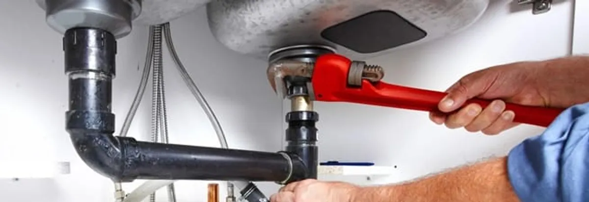 Garbage disposal repair technician tightening the sink drain and disposal connection in Salt Lake City, UT