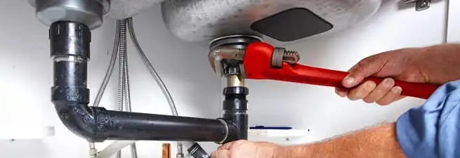 Garbage disposal repair technician tightening the sink drain and disposal connection in Salt Lake City, UT