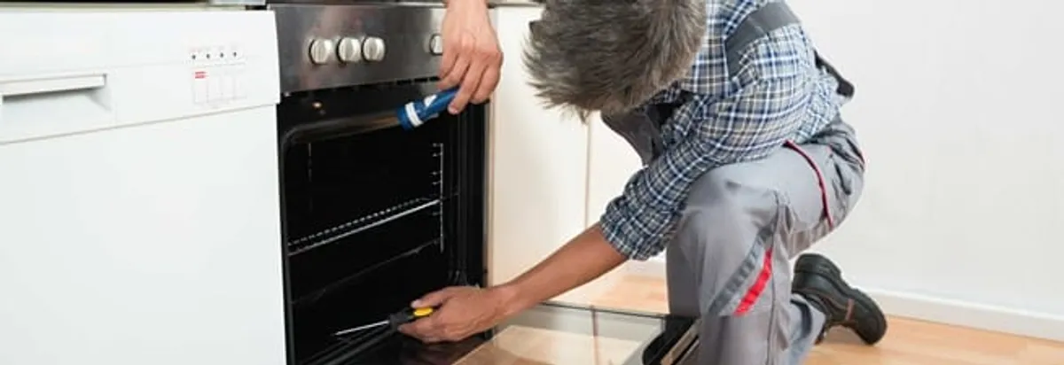 Oven repair technician inspecting and servicing an electric oven in Salt Lake City, UT