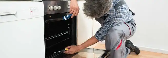 Oven repair technician inspecting and servicing an electric oven in Salt Lake City, UT